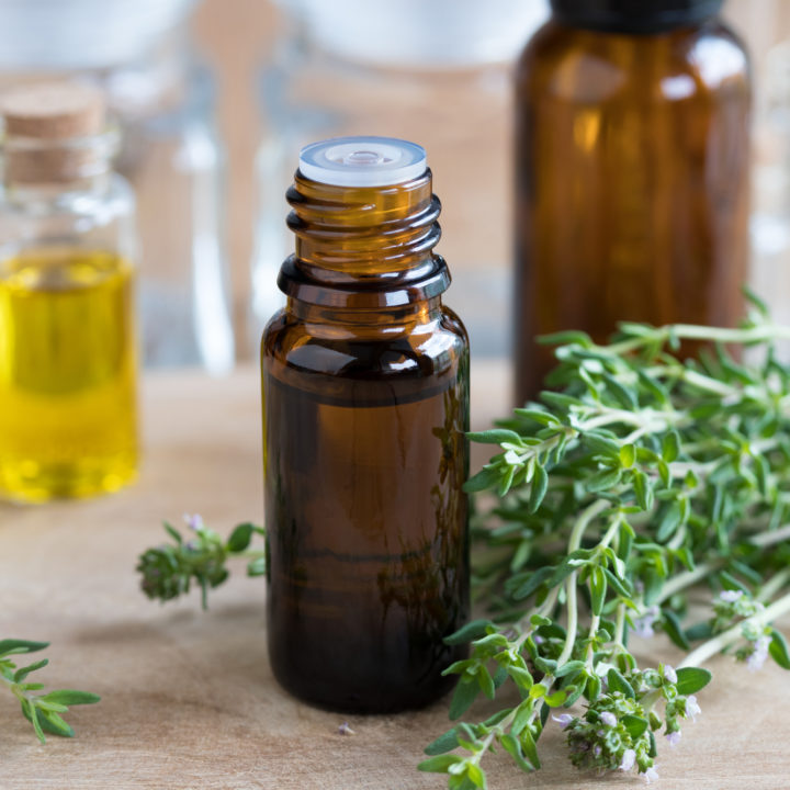 a bottle of thyme essential oil and twigs for homemade insect repellent